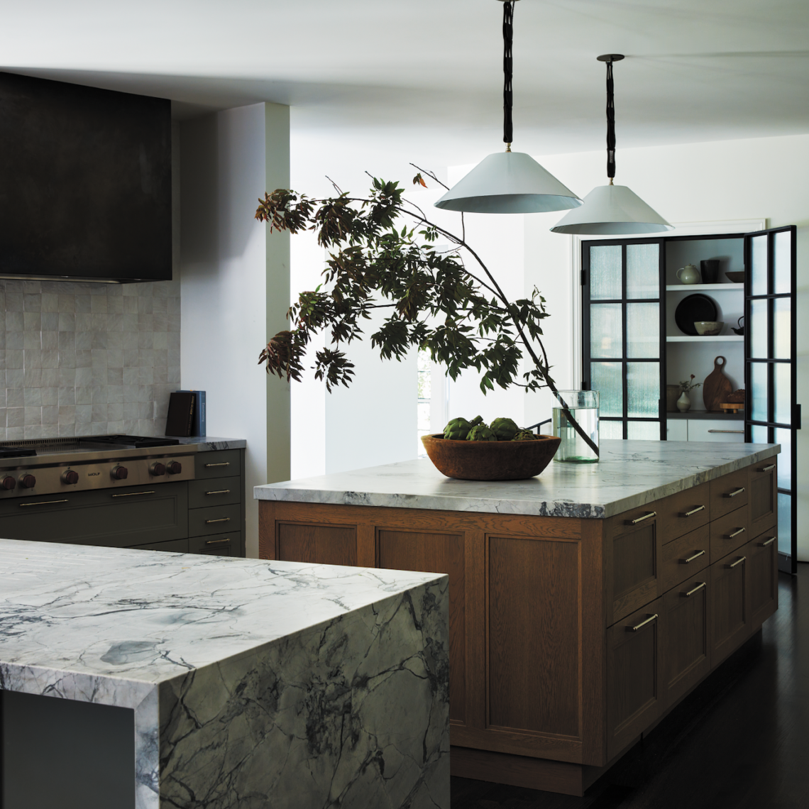 The kitchen deftly combines traditional features, like an oak island and floors stained a medium-brown tone, with modern elements such as the custom bronze hood. Photos by Tim Lenz.