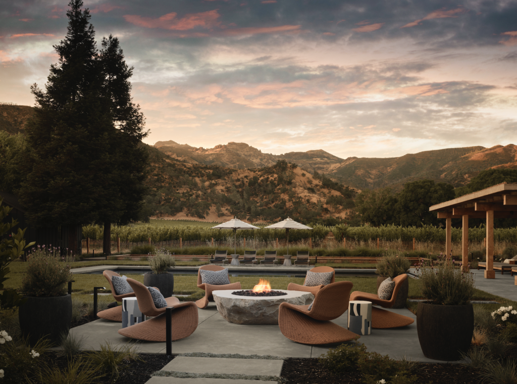 Near the pool, Four Hands outdoor rocking chairs and J Bradwells garden stools contribute to an idyllic spot to hang out and warm up by the firepit.