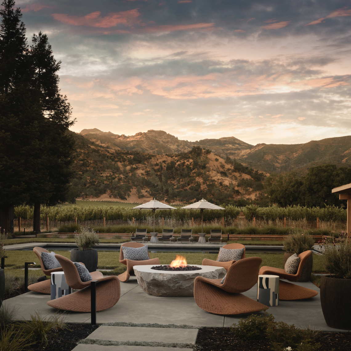 Near the pool, Four Hands outdoor rocking chairs and J Bradwells garden stools contribute to an idyllic spot to hang out and warm up by the firepit.